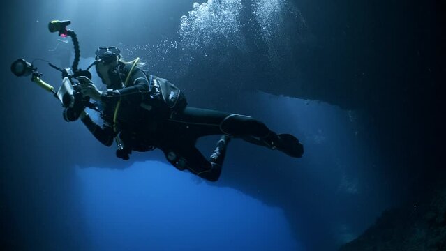 A female SCUBA Diver swims towards camera in an underwater cavern