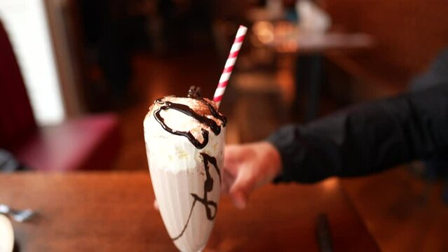 Person eating and drinking sugarily food dessert at restaurant. Man drinks milkshake and eats plate of pancakes