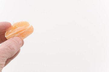 immagine con primo piano di mano che regge frutti di mandarino, clementina su superficie bianca