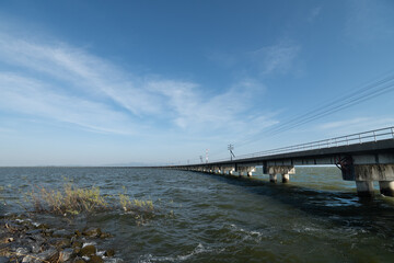 Thailand passengers train run on the floating railway bridge with blue sky in the lake of Pa Sak Jolasid dam at Lopburi province amazing in Thailand.