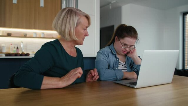 Down syndrome woman using computer with a help of her mother. Shot with RED helium camera in 8K.  