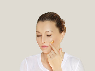 woman applying serum, lotion to her face