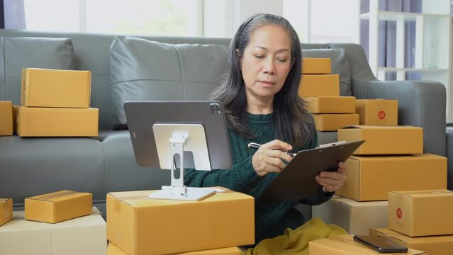 Startup small business entrepreneur or freelance using a laptop with box, checking orders from customers, matron runs an e-commerce business on websites and social media.