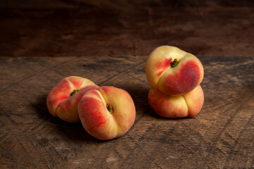 Several saturn peaches or flat peaches on wooden background.. © kostik2photo