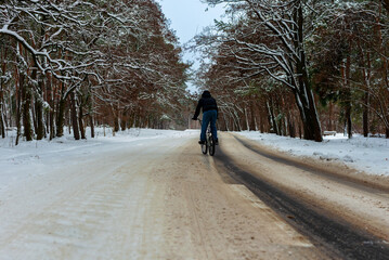 A cyclist rides on a slippery snowy road in winter.