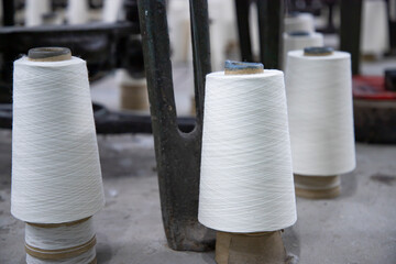 White Cotton Spools of Threads on the industrial knitting factory floor - obrazy, fototapety, plakaty