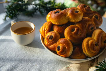 Plate with pile of homemade Swedish saffron buns lussekatter and cup of espresso coffee on linen...
