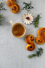 Homemade Swedish saffron buns lussekatter , cup of espresso coffee and candle on linen tablecloth .