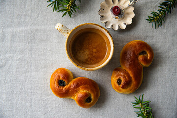 Homemade Swedish saffron buns lussekatter , cup of espresso coffee and candle on linen tablecloth .