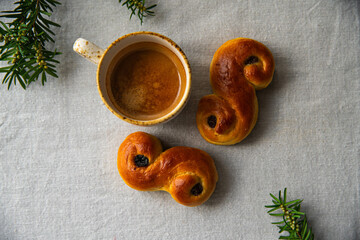 Homemade Swedish saffron buns lussekatter and cup of espresso coffee on linen tablecloth .