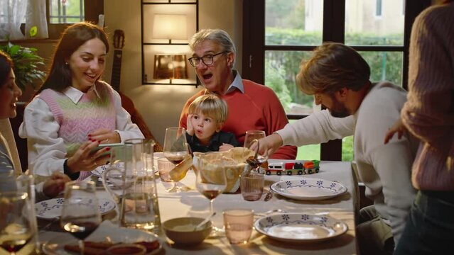 A family sitting at a dining table chatting and laughing decides to take a family selfie.
During the photo, the whole family makes funny faces