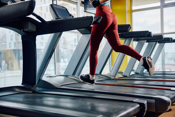 Unrecognizable woman jogging on treadmill in gym.