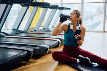 Young sportswoman drinking water during her gym workout.