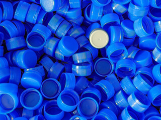 Grey plastic bottle caps on top to depict the concept of standing out from the crowd, dare to be different, odd man out, success or a leadership concept.