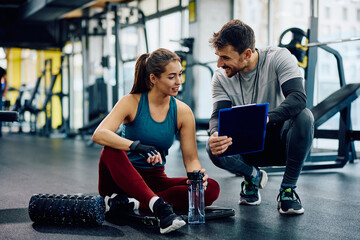 Personal instructor and athletic woman going through exercise plans in gym. - obrazy, fototapety, plakaty