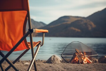  an orange chair sitting next to a fire pit on top of a sandy beach next to a body of water.