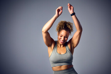 Studio Shot Of Woman Wearing Gym Fitness Clothing Dancing In Zumba Class On Grey Background