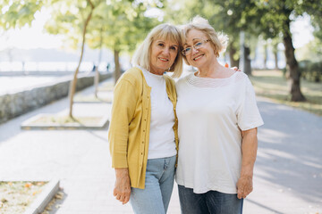 Two happy senior women blonde hairs or friends walking in the park