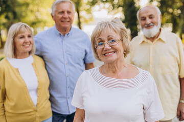 Senior blonde woman against the background of group of old people in park
