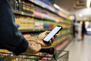 Closeup shot of a man checking his digital shopping list on his cellphone in a grocery store....