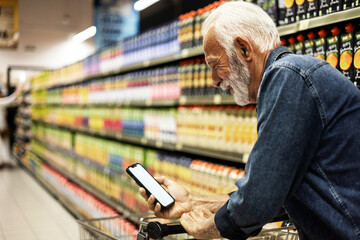 Mature man shopping healthy food in supermarket blur background. Close up view man buy products...