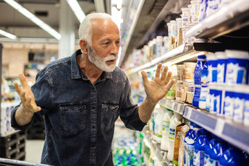 Cropped shot of senior man feeling shocked about rising grocery prices in the supermarket. Man...