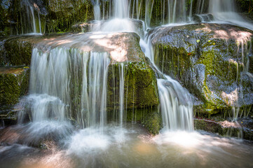 The waterfall flowing through mossy rocks and the water shot like a veil with a long exposure technique