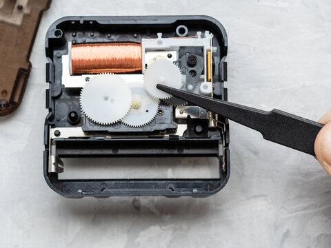 repairing faulty quartz movement from wall clock on concrete table close up