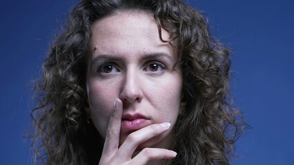 Thoughtful woman close-up face with deep meditative gaze and hand in chin. Person pondering decision