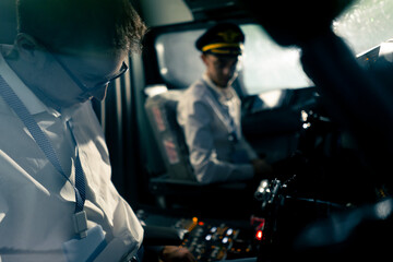 young pilots in the cockpit of the plane control the air transport during the flight the sun shines from the window in the far distance simulator - obrazy, fototapety, plakaty
