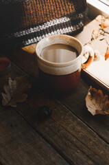 Large Cup of cappuccino on vintage brown background. Autumn, fall leaves, hot steaming cup of coffee and a warm scarf on wooden table background. Seasonal, morning coffee, Sunday relaxing and still l