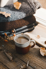 Large Cup of cappuccino on vintage brown background. Autumn, fall leaves, hot steaming cup of coffee and a warm scarf on wooden table background. Seasonal, morning coffee, Sunday relaxing and still l