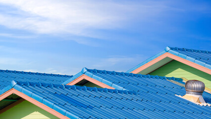 Blue fiber cement tile roofs in different level with roof ventilator against blue sky background