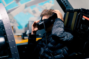 a guy sits in a flight simulator of a military plane before the start of the flight puts on virtual...