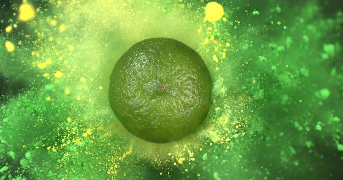 Super slow motion macro of fresh ripe bio organic green citrus lime fruit with splashing colors powder particles explosion isolated on black background at 1000fps.