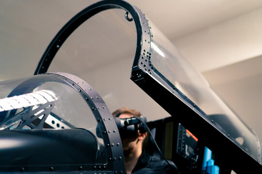 boy sitting in flight simulator of military plane wearing virtual reality glasses during flight entertainment