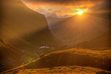 The sun goes down behind the mountain. Rays of light illuminate a mountain valley. Backlighting. A...