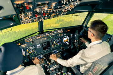 rear view of pilots in the cockpit of an airplane during flight control in a turbulence zone flight simulator - obrazy, fototapety, plakaty