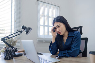 Young Asian business woman is having trouble controlling her online work in front of a laptop...
