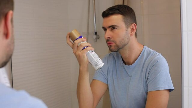 Man using hairspray  in front of the mirror 