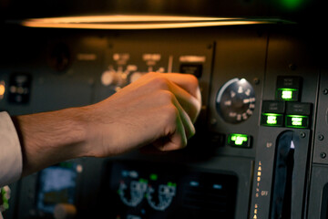 close-up hand of the pilot captain presses the buttons on the control panel to start the engine of...