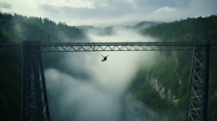 Bungee jumping sportsman jumps from a metal railway bridge over a foggy gorge. - Powered by Adobe