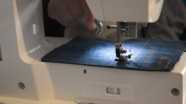 Man and child using a sewing machine with a blue garment, for repair work, customization, creation, upcycling