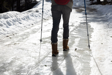Woman Hiker Walking Carefully over part of Frozen Icy Road in Winter in Snowshoes and with help of...