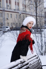 Woman with big braid in brown retro fur coat in winter street with snow. Winter cold weather. Girl...