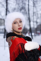 Woman with big braid in brown retro fur coat in winter street with snow. Winter cold weather. Girl...