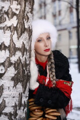 Woman with big braid in brown retro fur coat in winter street with snow. Winter cold weather. Girl...