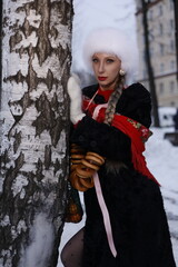 Woman with big braid in brown retro fur coat in winter street with snow. Winter cold weather. Girl...
