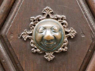 Verzierung einer Haustür mit einem runden Gesicht aus Metall
