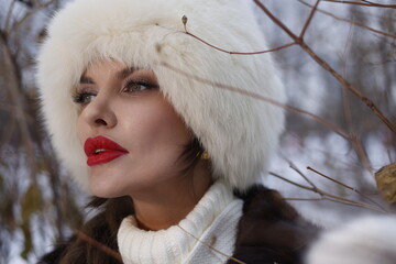 Woman with big braid in brown retro fur coat in winter street with snow. Winter cold weather. Girl...